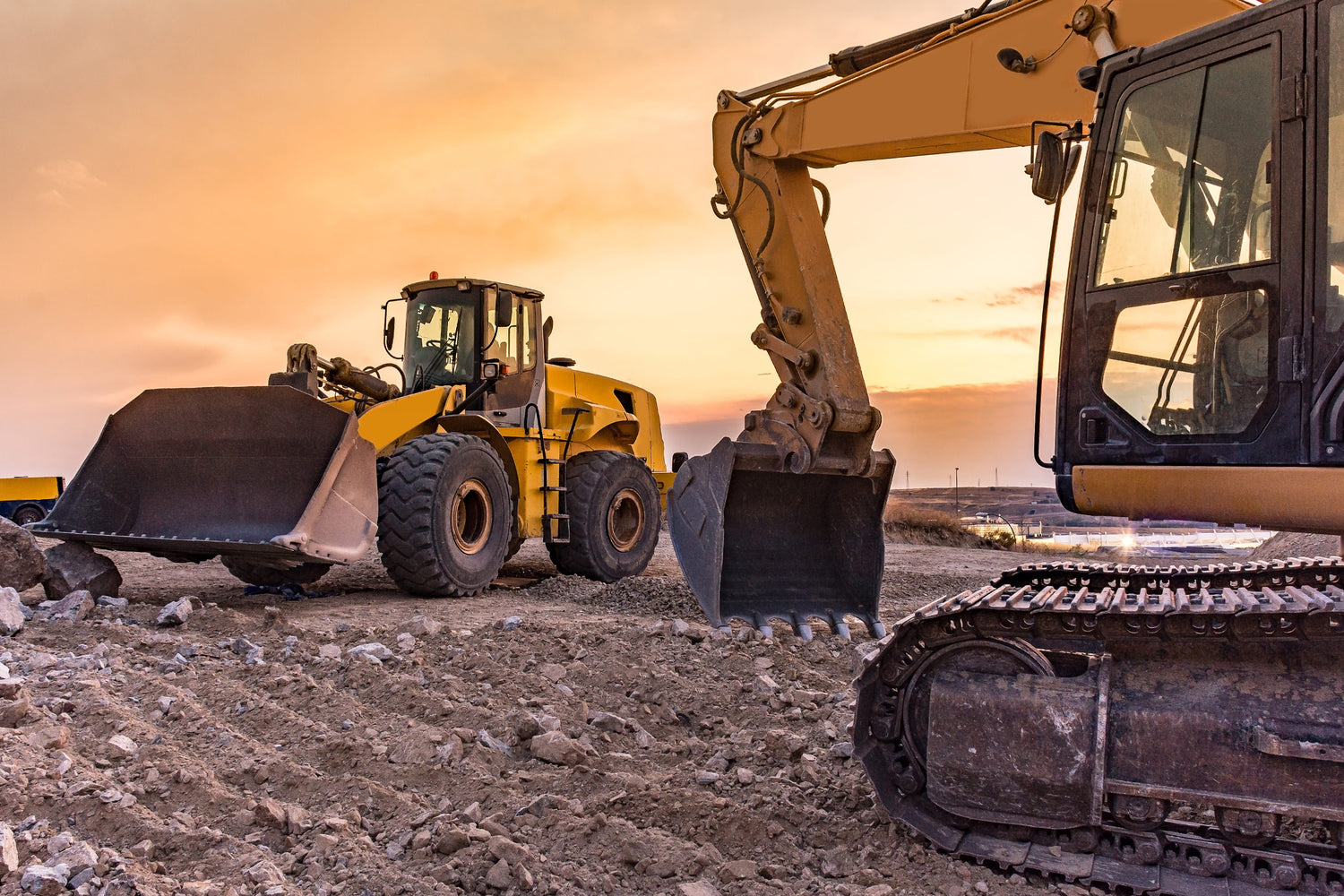 Two construction vehicles, a bulldozer and an excavator, on a construction site.