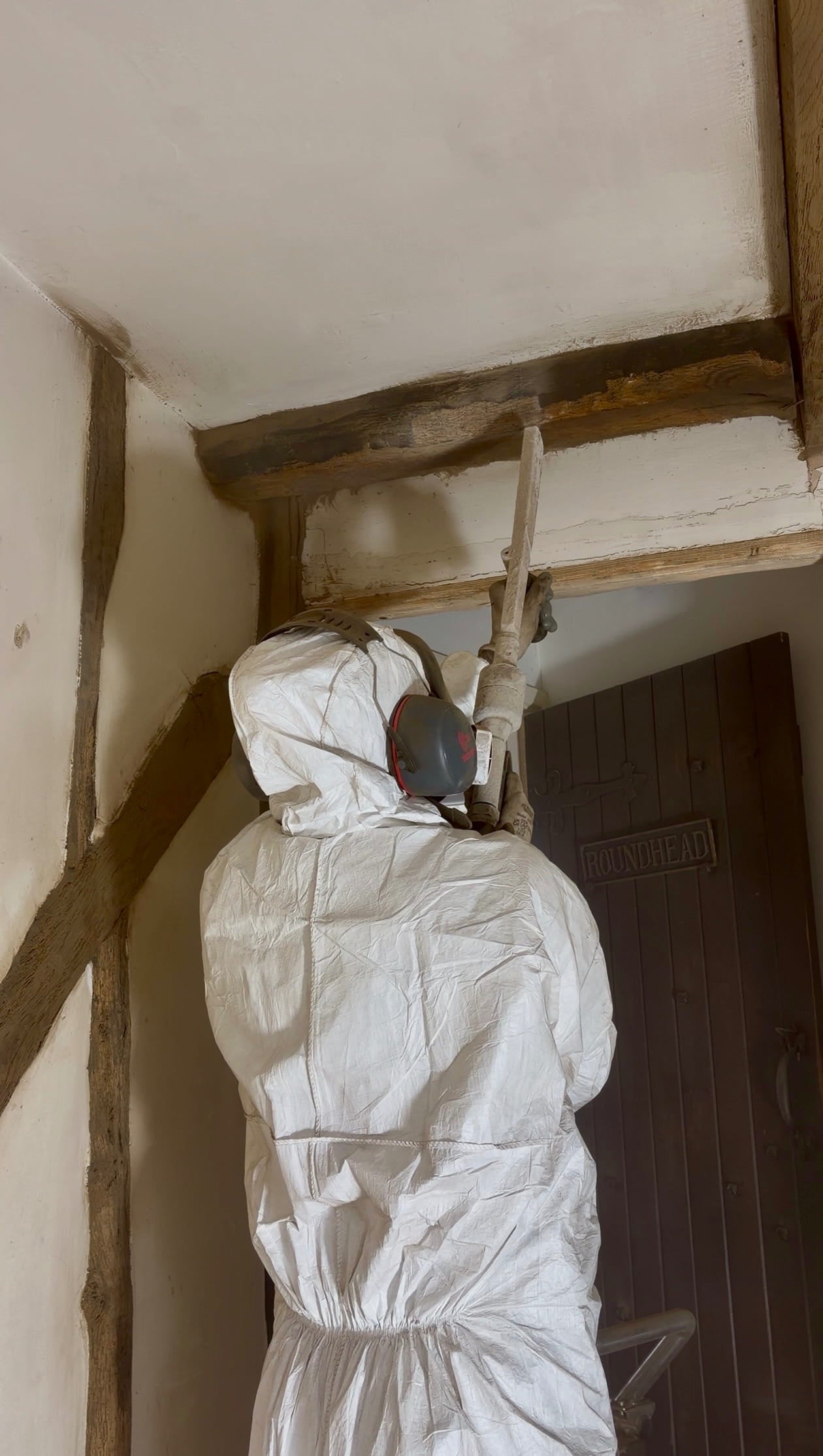 Dry ice blasting wooden beam restoration holding dry ice blaster upwards towards beam