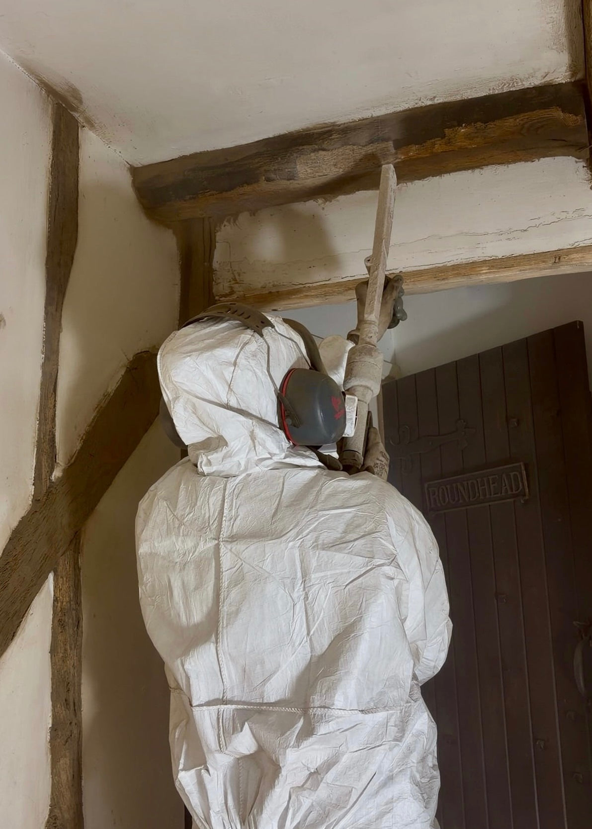 Dry ice blasting wooden, beam restoration dry ice blasting, person pointing dry ice blaster towards wooden beam
