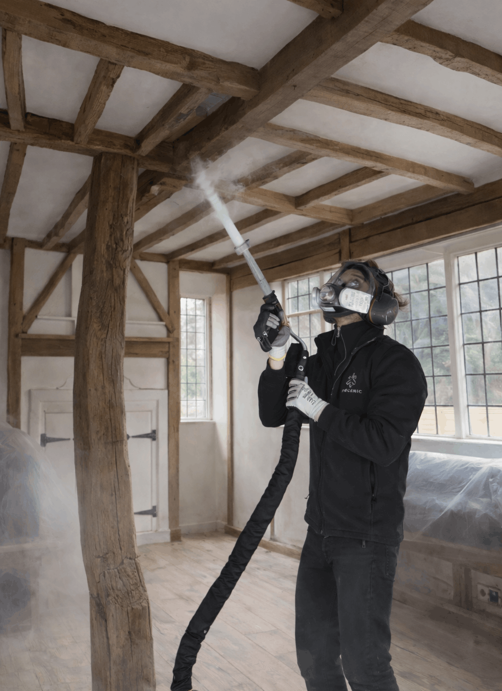 Person dry ice blasting wooden beams in cottage
