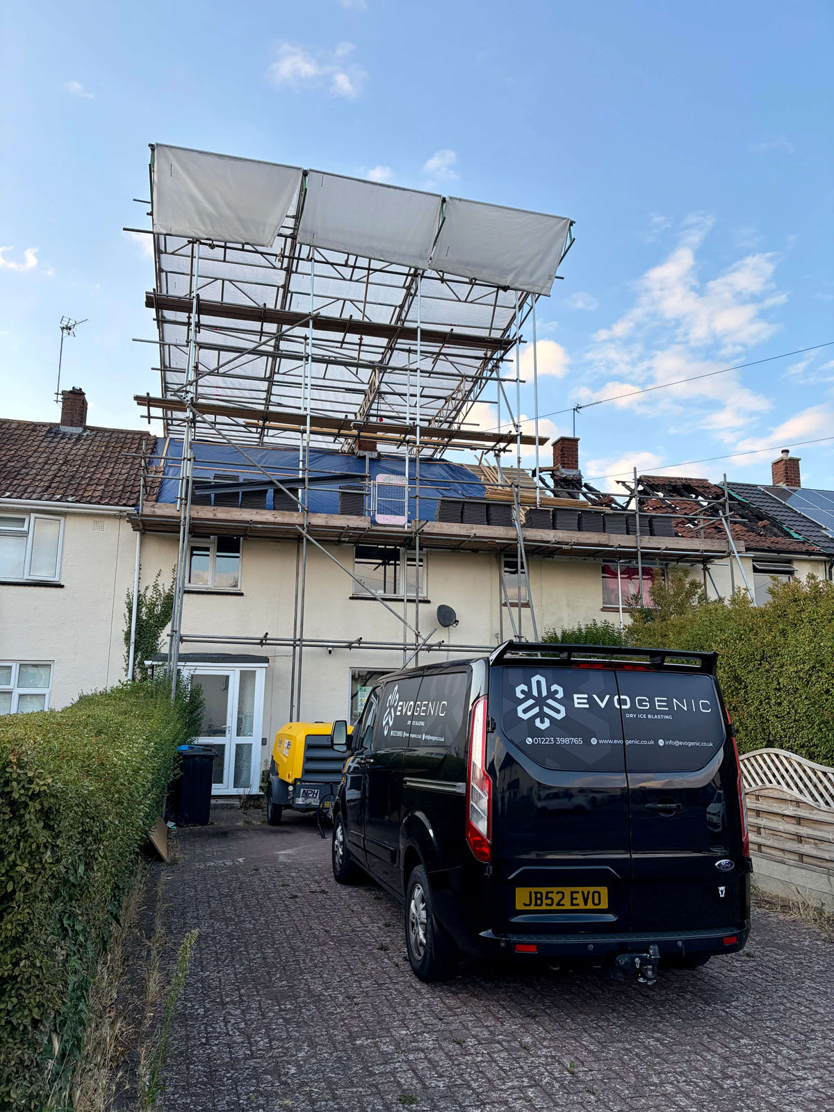 EVOGENIC van parked outside fire damaged property with scaffolding preparing for fire damage restoration dry ice blasting